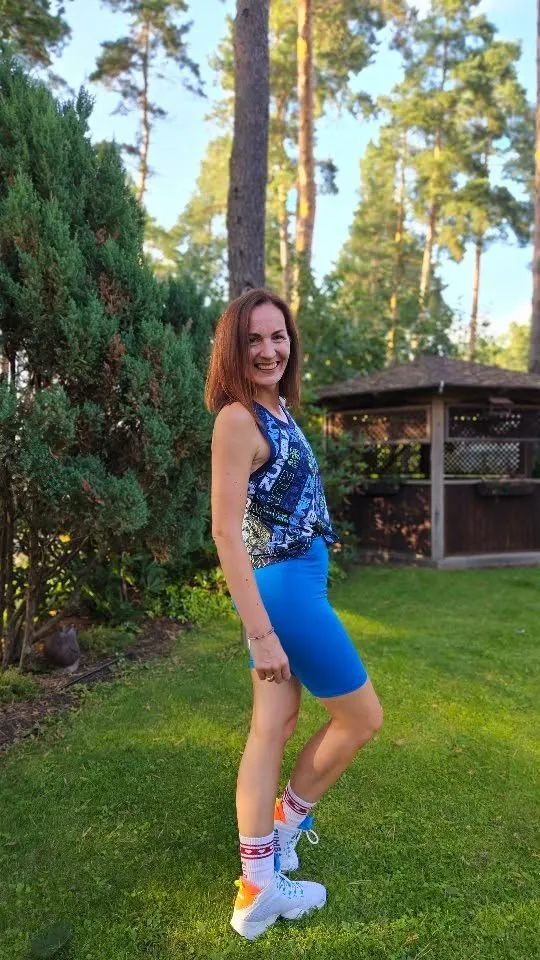 Sanita Zumba tērpā dārzā starp priedēm